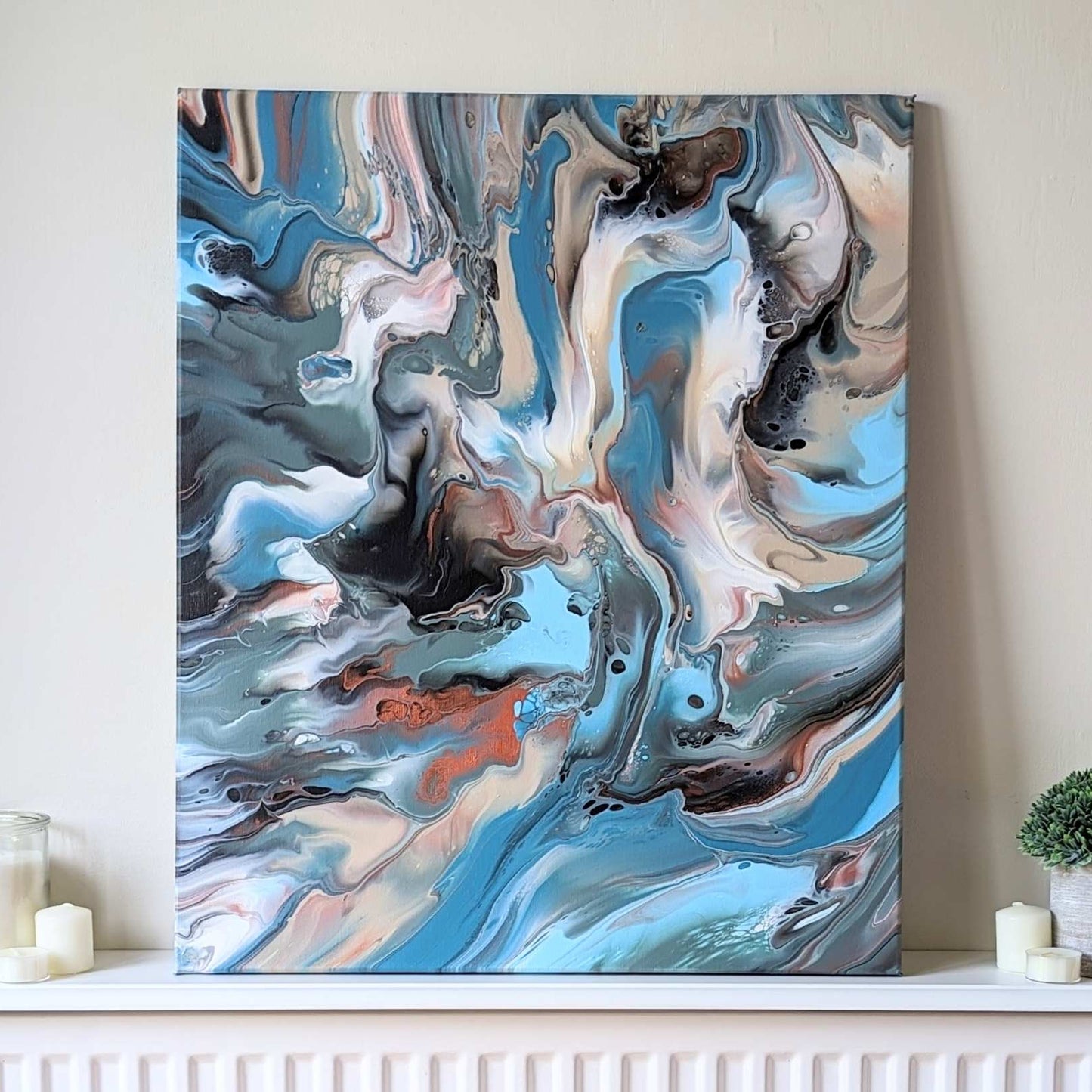 Abstract painting on a wall above a radiator with candles and a plant.
