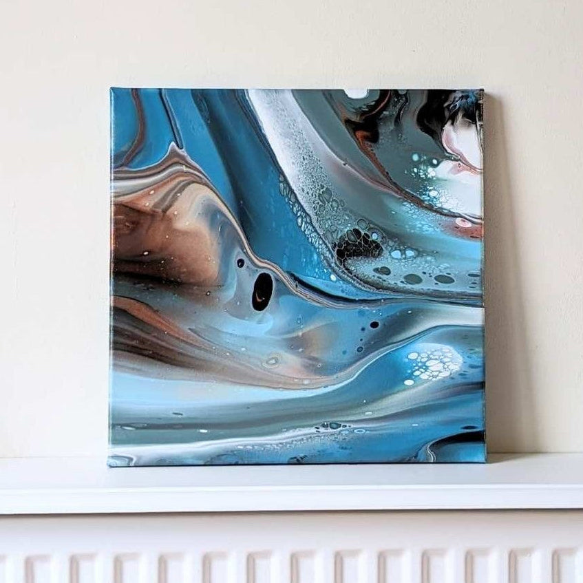 Abstract art piece on a white wall above a radiator with candles and a plant.