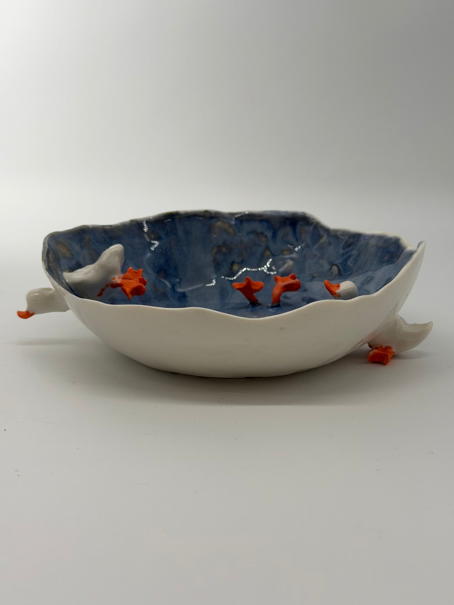 Ceramic wall art piece with fish design on a plain background