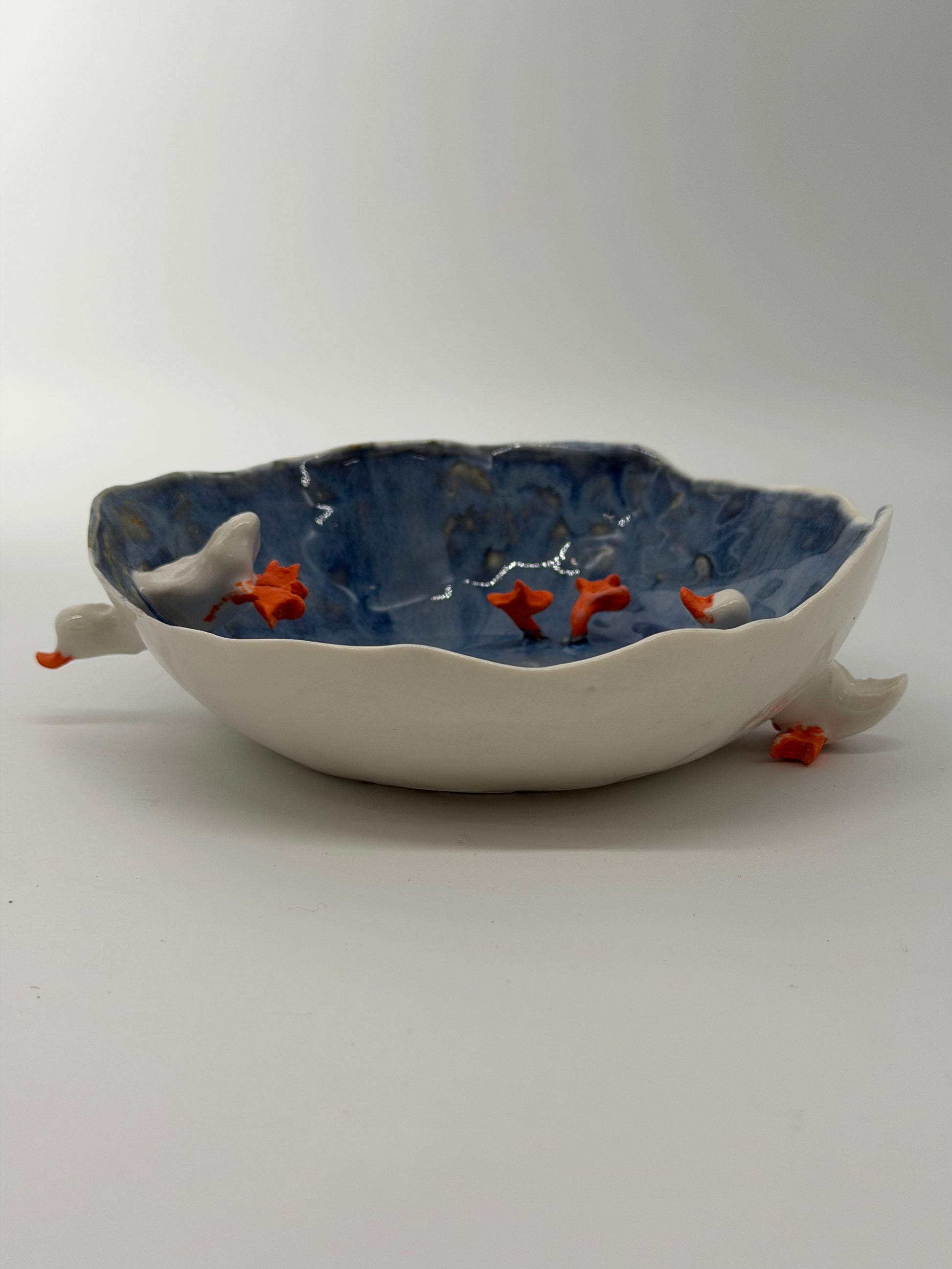 Ceramic wall art piece with fish design on a plain background