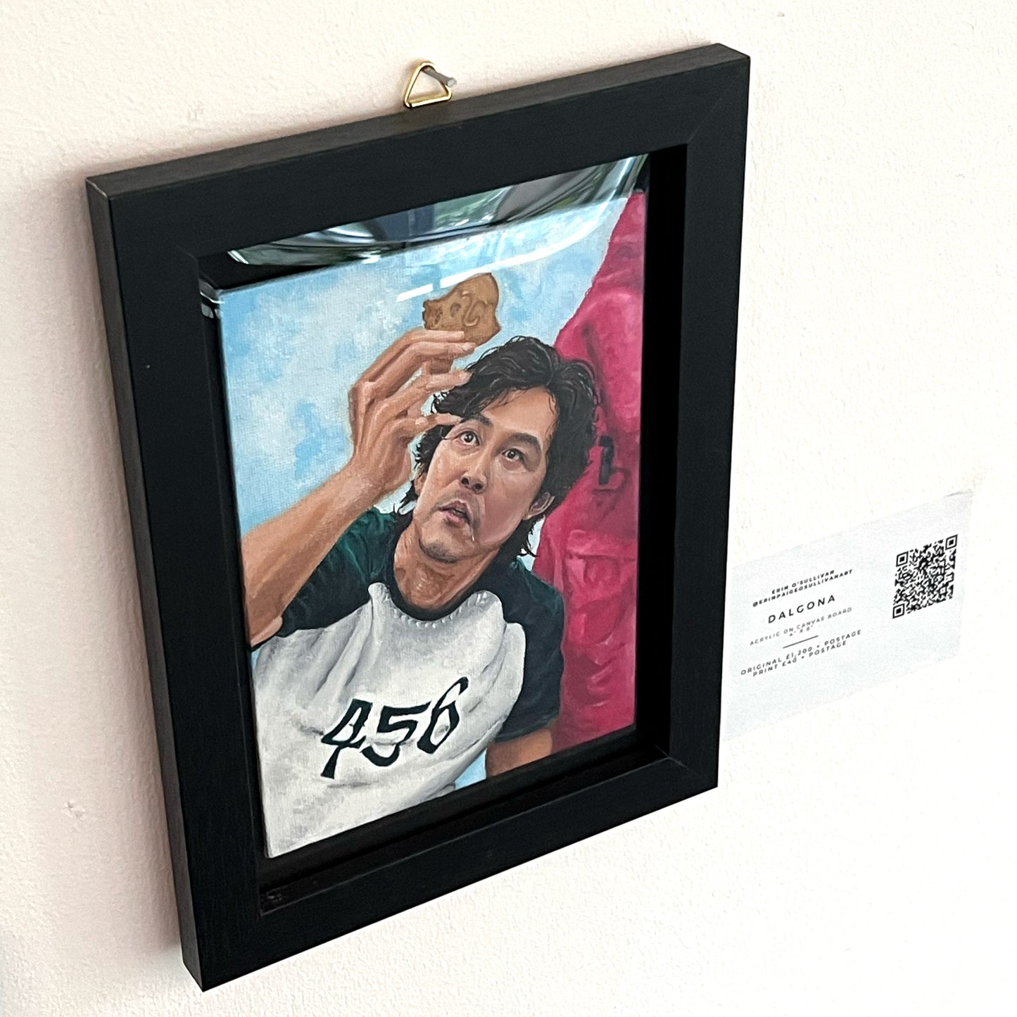 Realistic portrait painting of Lee Jung-jae as Seong Gi-hun from Squid Game, focusing on his player number 456 and the dalgona honeycomb challenge, available at HEADS Art Gallery.