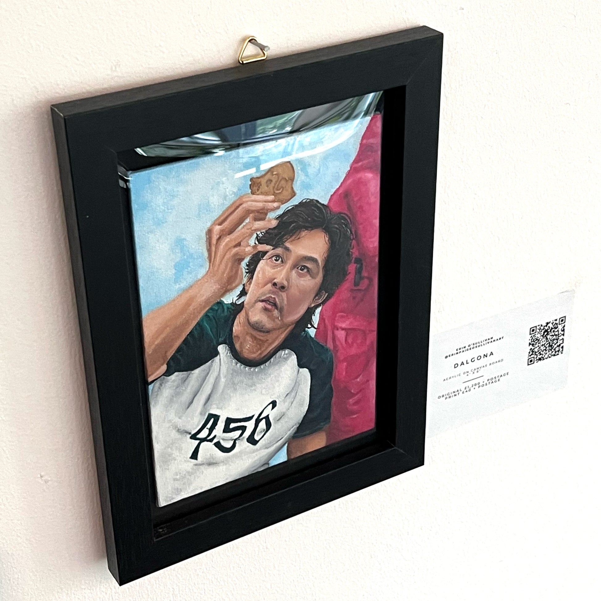 Realistic portrait painting of Lee Jung-jae as Seong Gi-hun from Squid Game, focusing on his player number 456 and the dalgona honeycomb challenge, available at HEADS Art Gallery.