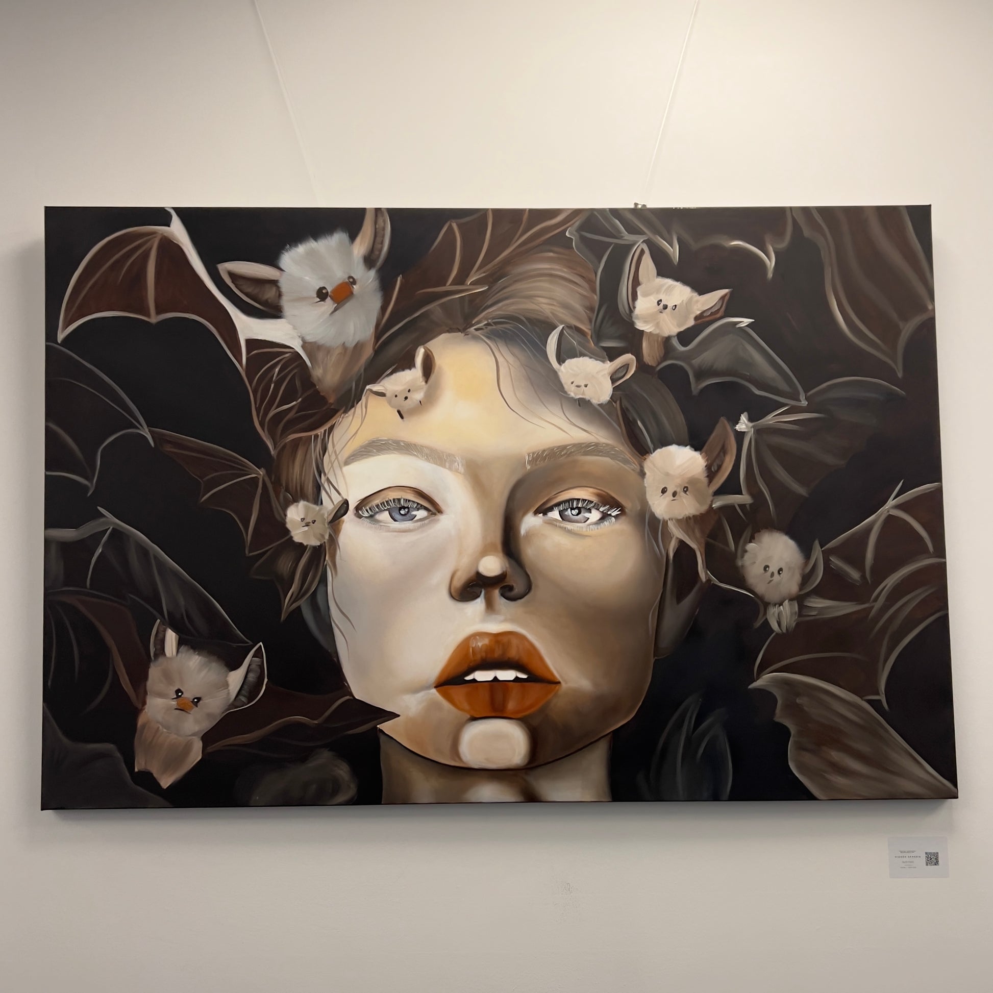 Painting of a woman's face surrounded by numerous small, fluffy white bats against a dark background, available at HEADS Art Gallery.
