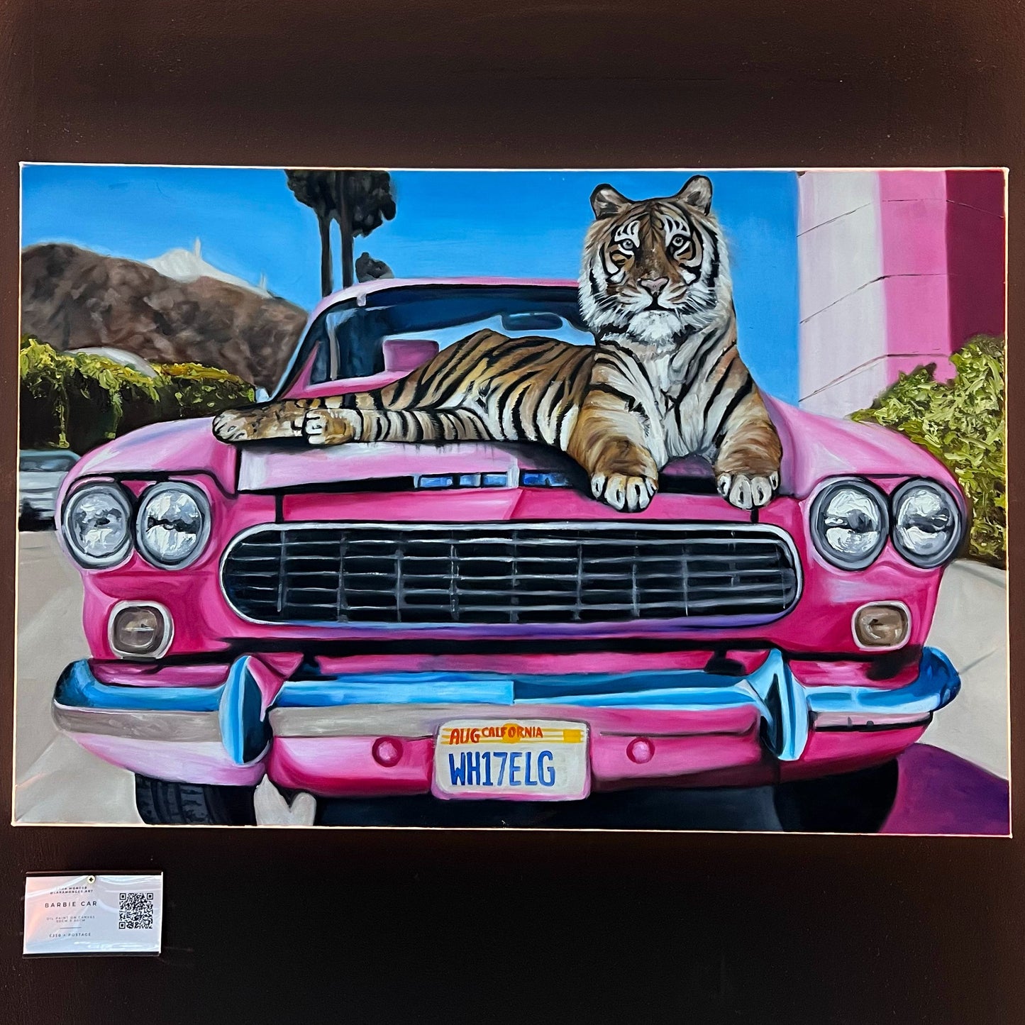 Realistic oil painting of a majestic Bengal tiger lounging on the hood of a vibrant pink vintage car with a California license plate, available at HEADS Art Gallery.