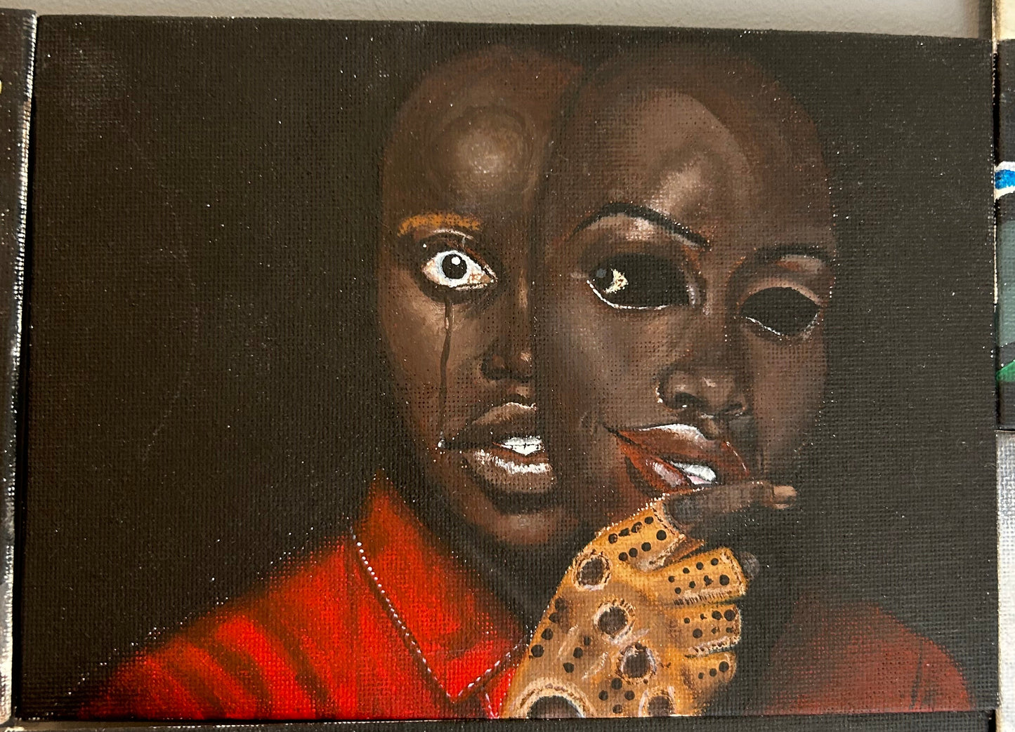 Double-exposure portrait inspired by the film "Us," showing two versions of a character's face with a tear and a gloved hand on a black background, available at HEADS Art Gallery.